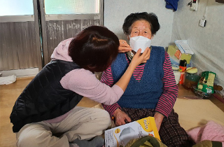 요양사가 할머니께 마스크를 쒸워드리는 사진